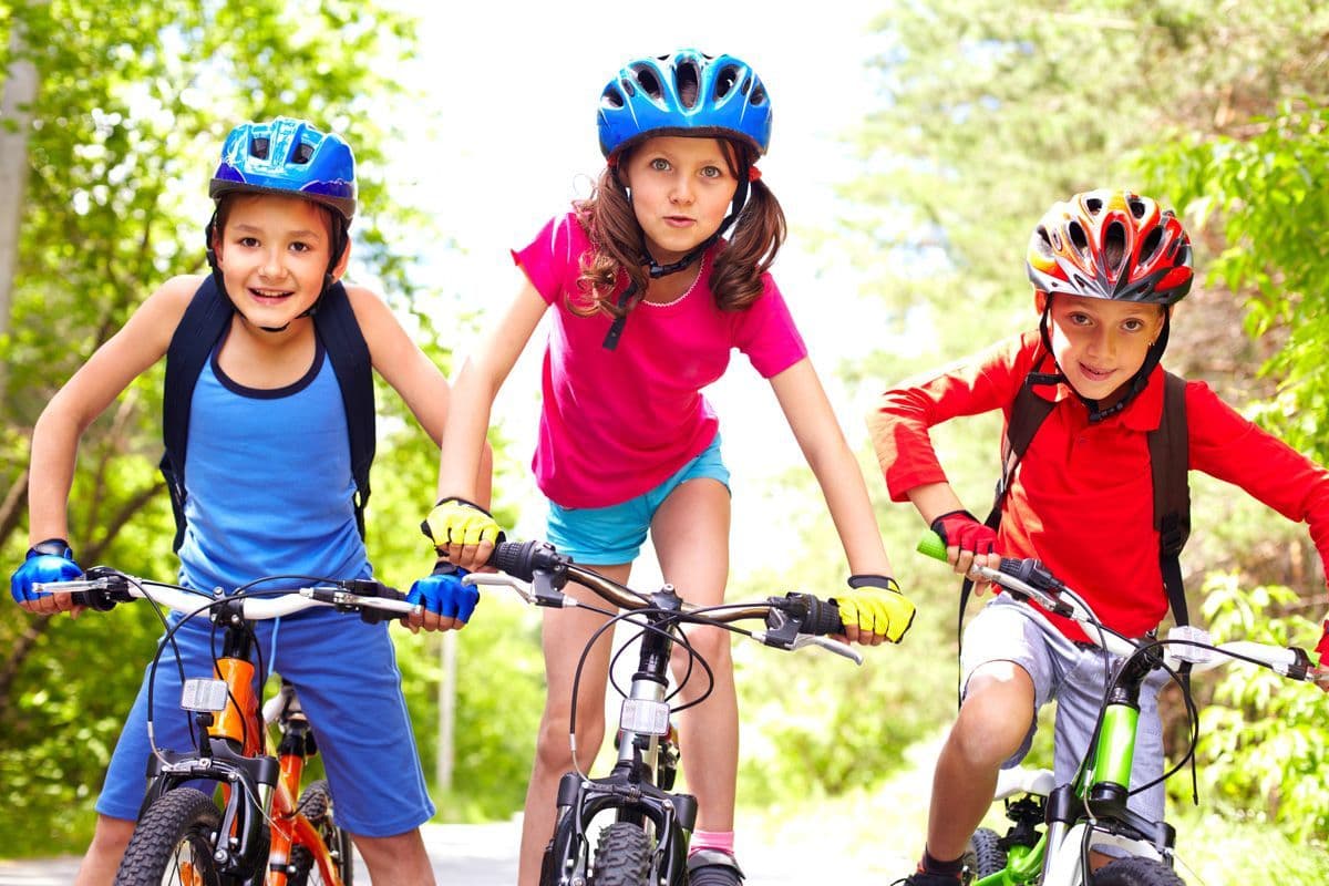 Drie lachende kinderen met een beperking, vrolijk op een fiets